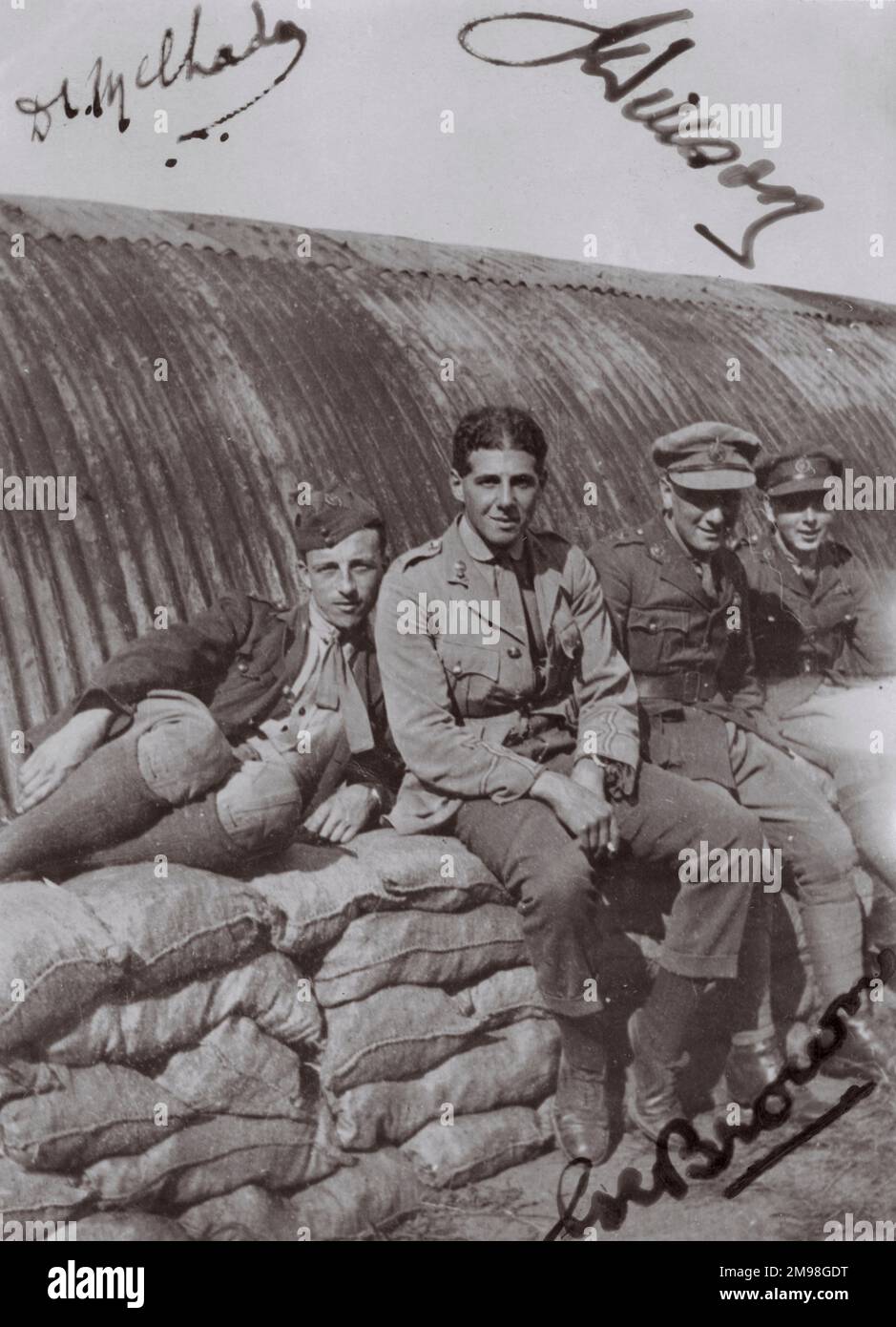 Vier Crewmitglieder des Royal Flying Corps entspannen sich auf einem Haufen Säcke vor einer Welleisenhütte, irgendwo in Nordfrankreich während des Ersten Weltkriegs. Drei von ihnen haben ihre Namen auf dem Foto unterschrieben. Stockfoto