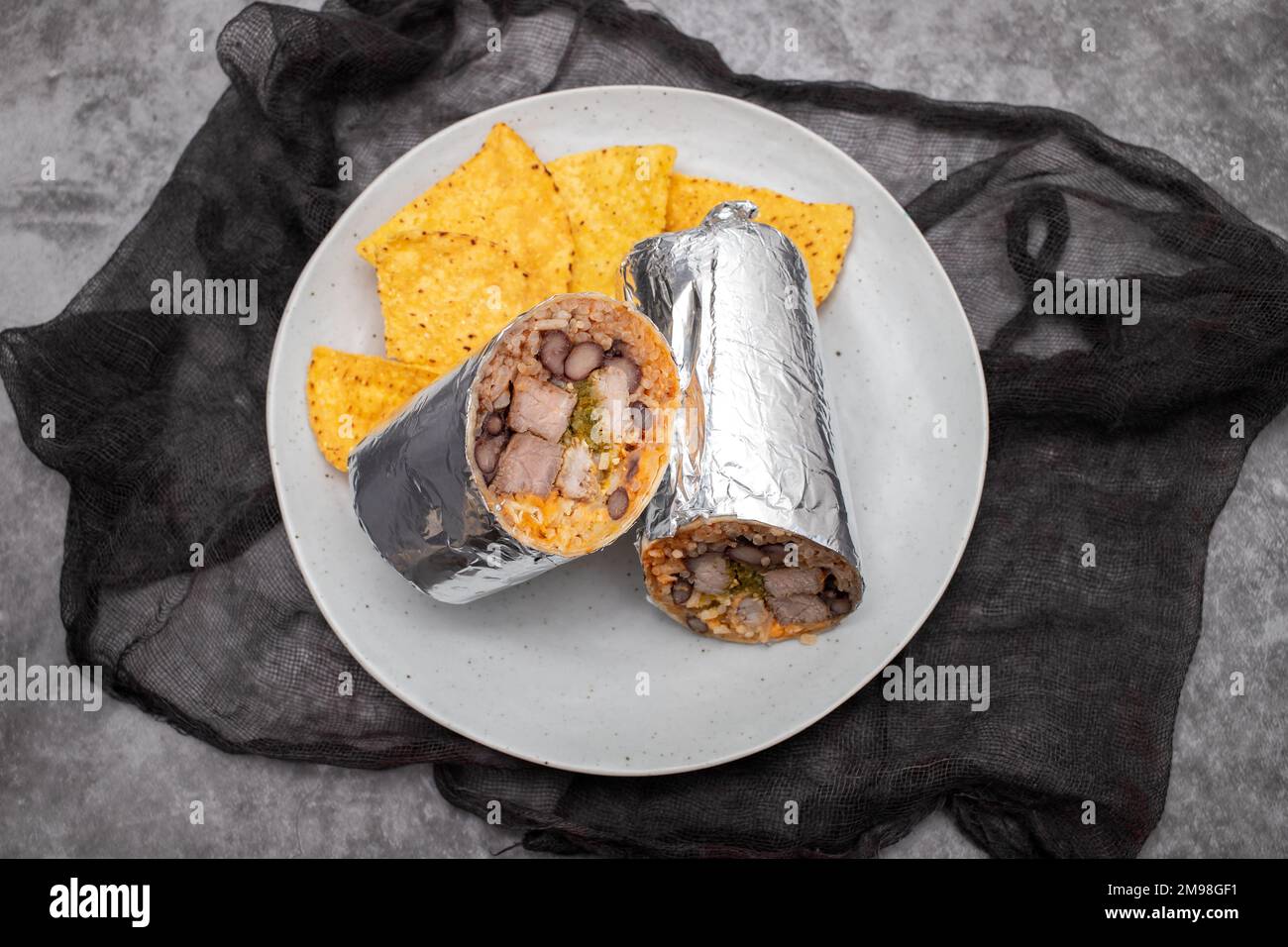 Mexikanischer Rindfleischburrito auf einem kleinen Teller mit Chips Nachos Stockfoto