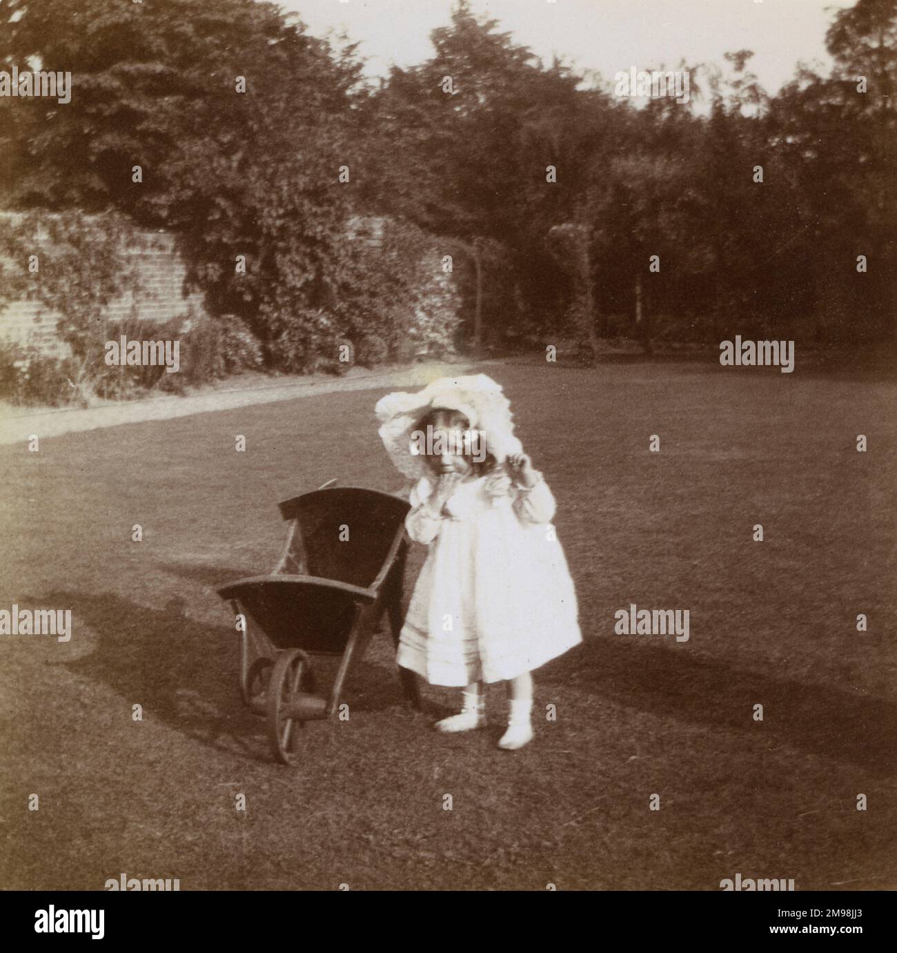 Kleines Mädchen (Violet Auerbach) mit einer Schubkarre im Garten ihres Hauses, 1 Carlton Road, Ealing, West London. Stockfoto