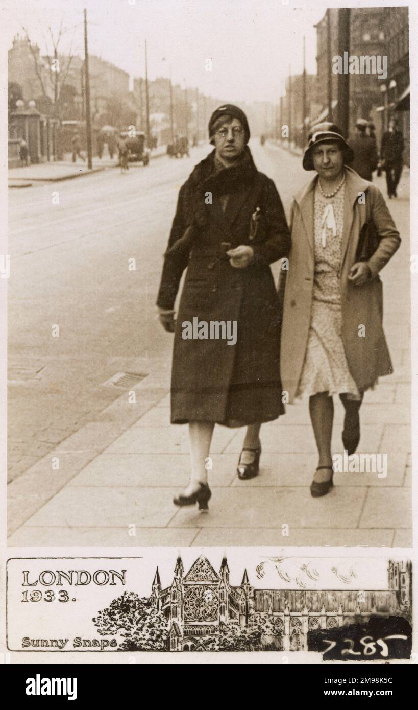 Ein paar Damen, die eine London Street entlangspazieren, scheinen den Fotografen erwischt zu haben, und die Dame auf der linken Seite sieht bereit aus, ihre Gedanken zu dieser Angelegenheit bekannt zu machen... Stockfoto
