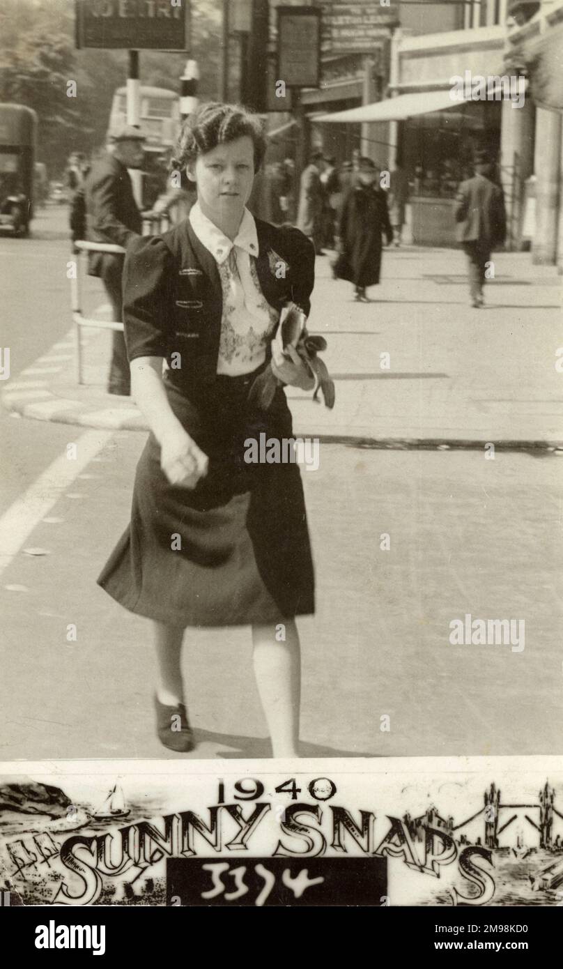 Junge Dame (Frau Wiseman), die absichtlich eine Straße in Nord-London hinuntergeht - sie trägt eine sehr elegante und unverwechselbare, bestickte Bluse und ein Outfit aus Jerkin und hat ihre Haare mit einer permanenten Welle. Stockfoto