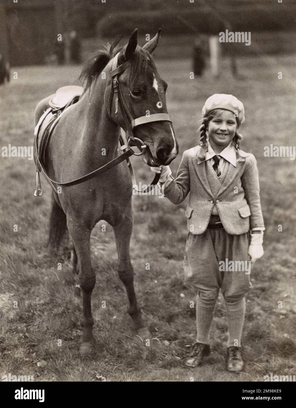 Lächelndes Mädchen mit ihrem Pony auf einem Feld, Mai 1934. Stockfoto