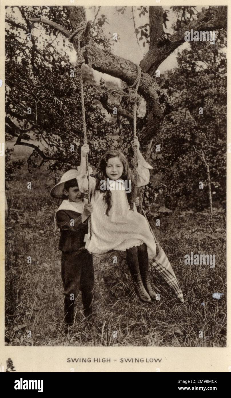 „Swing High – Swing Low“ – Bruder und Schwester spielen auf einer Schaukel in ihrem Garten. Stockfoto