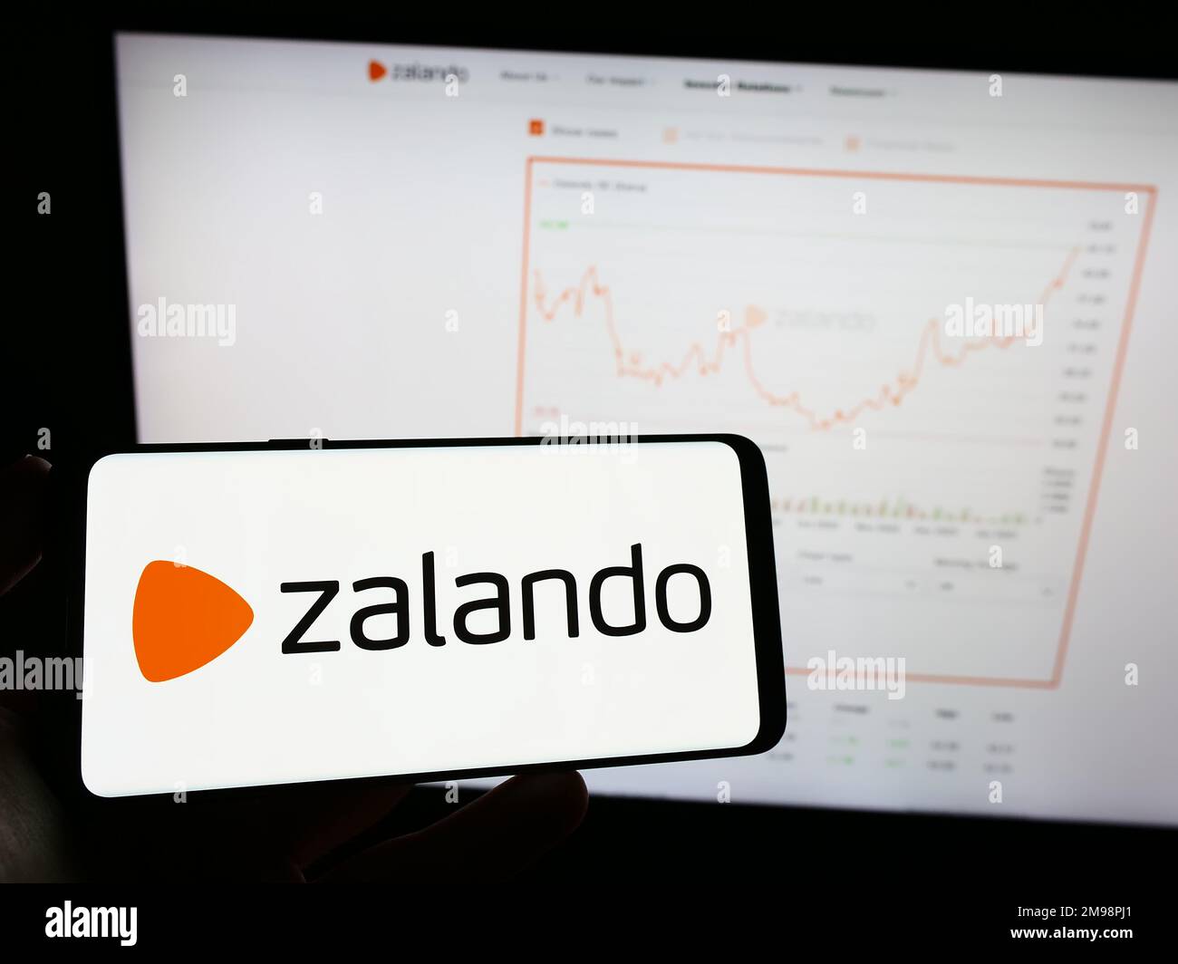 Person, die ein Mobiltelefon mit dem Logo des deutschen E-Commerce-Unternehmens Zalando SE auf dem Bildschirm vor der geschäftlichen Webseite hält. Konzentrieren Sie sich auf das Display des Telefons. Stockfoto