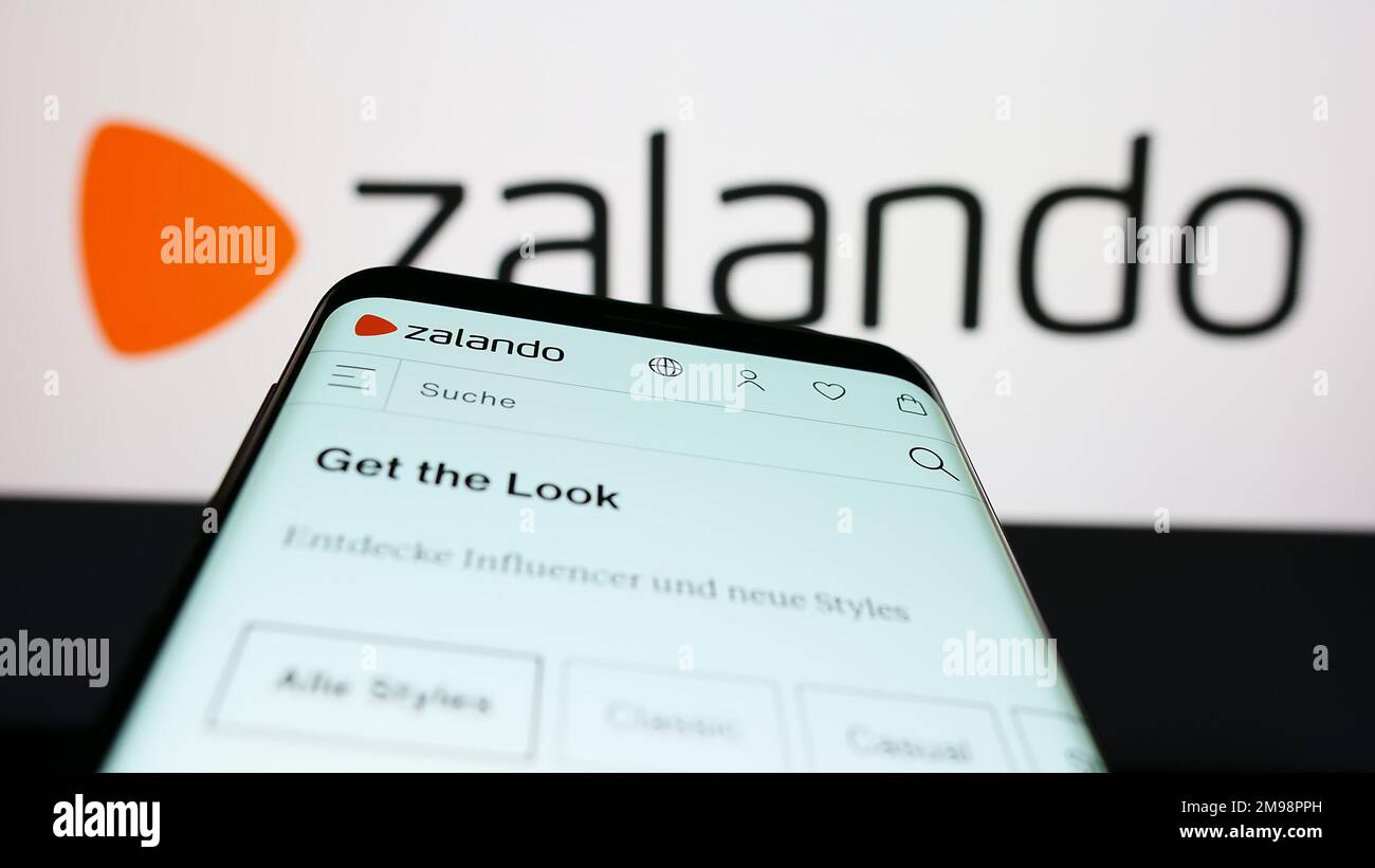 Mobiltelefon mit Website des deutschen E-Commerce-Unternehmens Zalando SE auf dem Bildschirm vor dem Firmenlogo. Fokus auf oberer linker Seite des Telefondisplays. Stockfoto