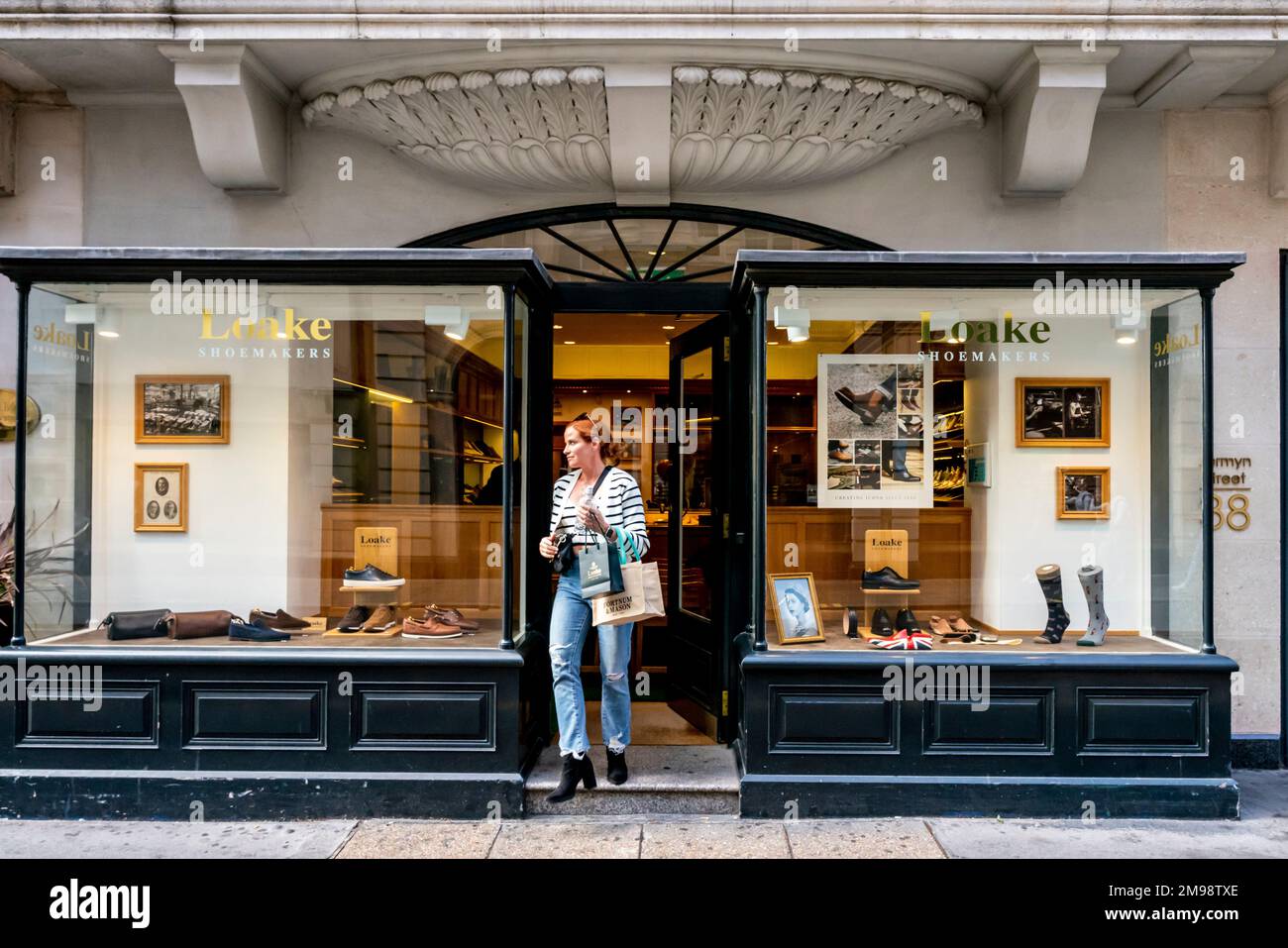 Eine modische junge Frau verlässt Loake Shoemakers, Jermyn Street, London, Großbritannien. Stockfoto