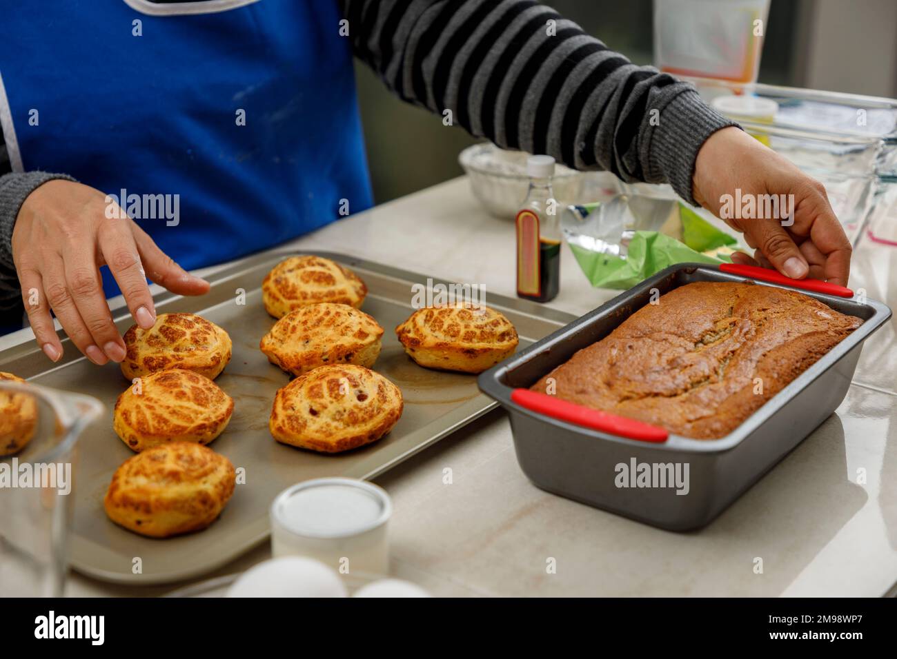 Frauenhände, die das Brot und die Zimtschnecken arrangieren, die sie gerade zu Hause gebacken hat Stockfoto