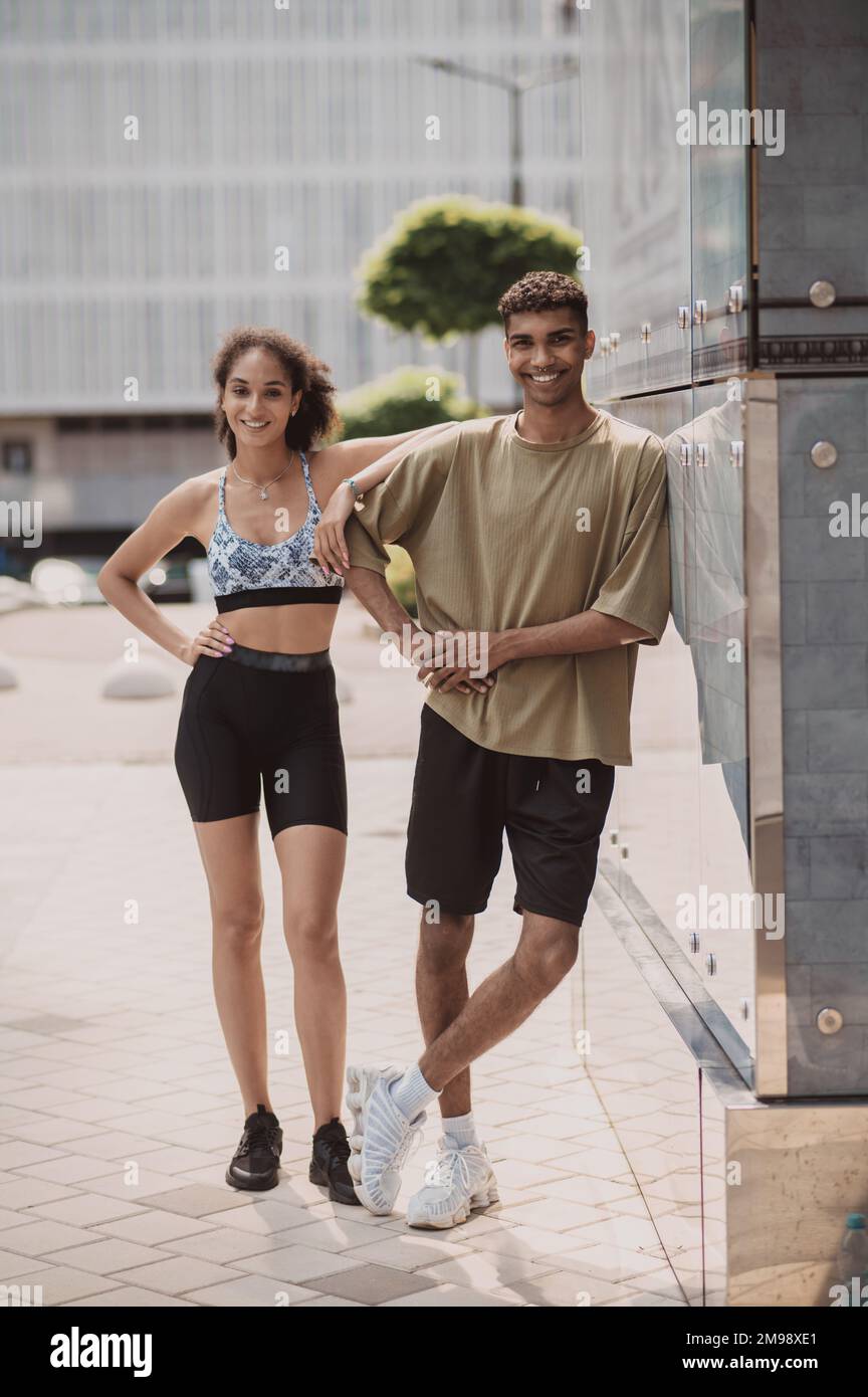 Ein sportliches Paar, das sich für die Kamera in der Nähe eines Bürogebäudes posiert Stockfoto