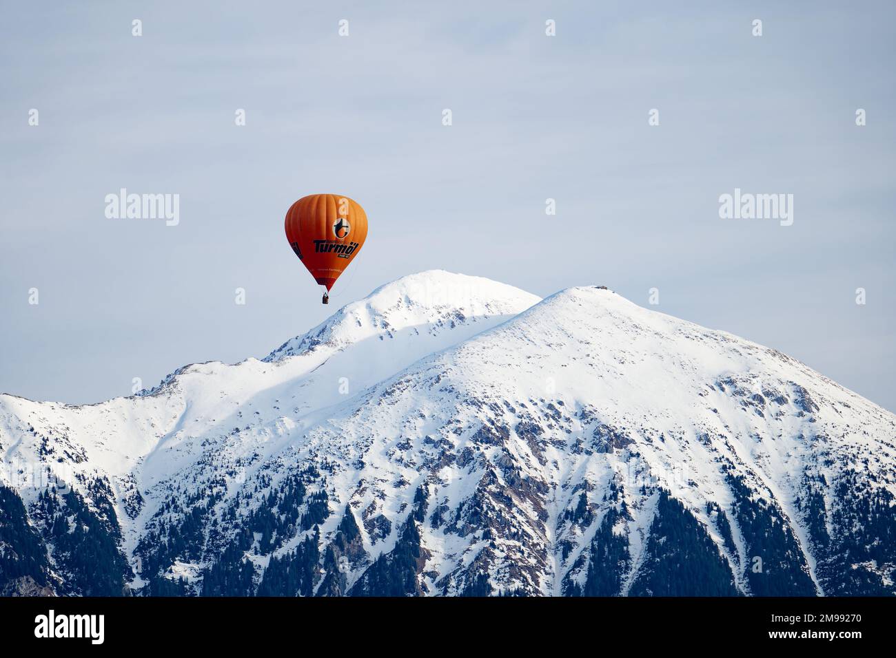 Ein Heißluftballon, der um die schneebedeckten Berge fliegt. Eine Wintergeschichte für romantische Erlebnisse. Berge mit Schnee im Hintergrund. Stockfoto