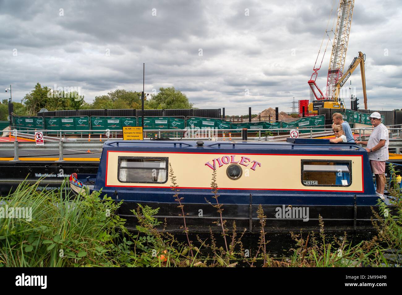 Harefield, London Borough of Hillingdon, Vereinigtes Königreich. 30. Juli 2022. HS2 Werke neben dem Grand Union Canal in Harefield machen es jetzt für Schmalboote unangenehm, an ihrer temporären Straße vorbei zu fahren, die über den Kanal hinausragt. HS2 haben zahlreiche Bäume im Bereich der Hochgeschwindigkeitsbahnverbindung gehackt. Umweltschützer haben Bedenken hinsichtlich der HS2 Werke und der Auswirkungen, die sie auf einige der Trinkwässer in der Gegend haben. Kredit: Maureen McLean/Alamy Stockfoto