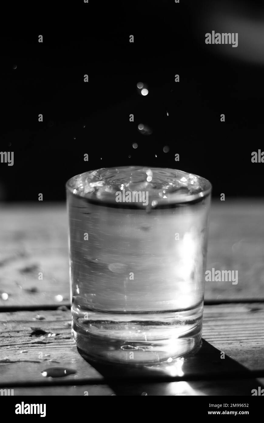Glas mit Wasser und Tropfen darüber Stockfoto