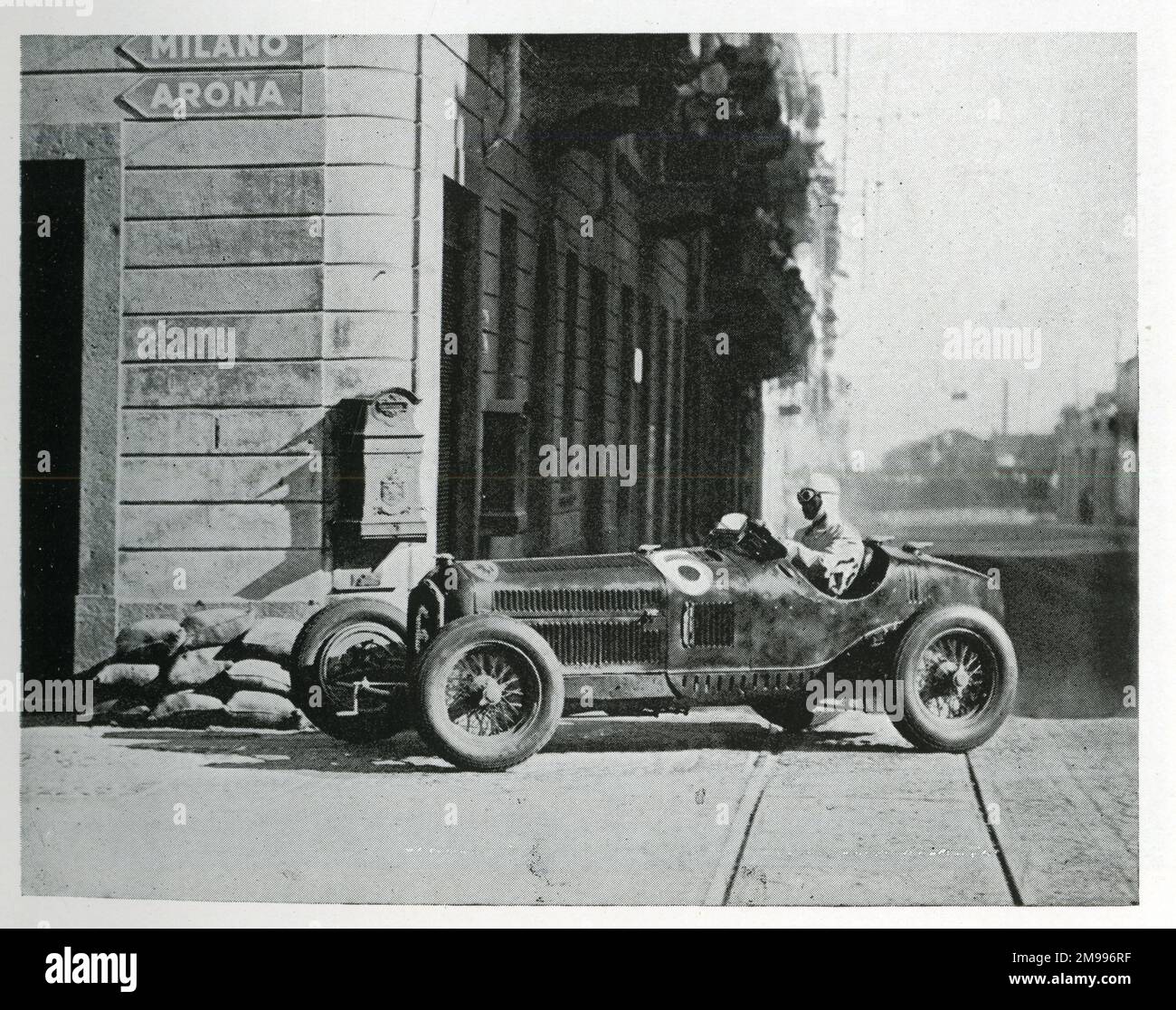 Achille Varzi fährt einen Alfa-Romeo im Biella-Rennen - hier über Straßenbahnlinien, in der Nähe von Sandsäcken, die platziert wurden, um einen Briefkasten zu schützen, der aus der Wand ragt. Stockfoto