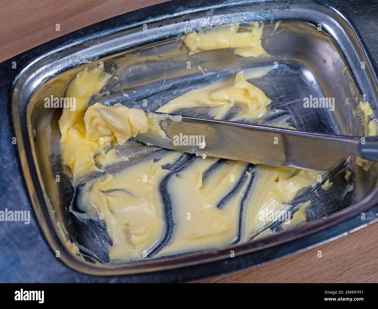 Butter und Messer in die Butterdose geben Stockfoto