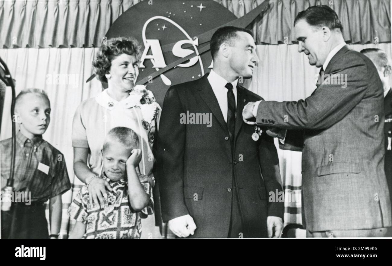 Astronaut Virgil ?Gus? Grissom erhält die NASA Distinguished Service Medal von James E. Webb, NASA Administrator, richtig, während einer Nachrichtenkonferenz in Cape Canaveral, am Tag nach seinem Suborbitalflug, der eine Höhe von 118 Meilen am 22. Juli 1961 erreicht hatte. Grissoms Frau Betty und ihre beiden Söhne Scott und Mark. Stockfoto