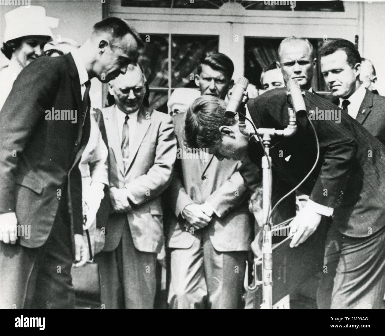 Präsident John F. Kennedy bemüht sich, die National Aeronautics and Space Administration Service Medal zurückzuholen, die er bei der Überreichung der Auszeichnung an Commander Alan Shepard Jr. Left in einer Zeremonie im Rosengarten des Weißen Hauses in Washington DC am 8. Mai 1961 verliehen hat. Von links sehen Sie Mrs. Louise Shepard, Dr. Hugh Dryden und die Astronauten Walter Schirra, John Glenn und Leroy Cooper. Stockfoto