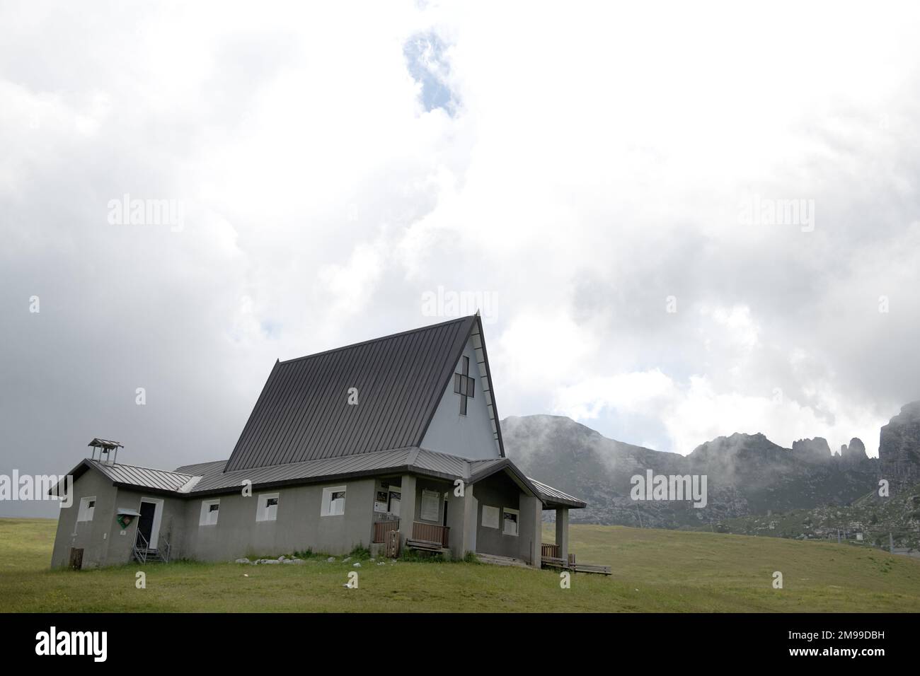 Christliche Kirche, umgeben von weißen Wolken auf den Alpen rund um den Comer See, Lombardei, Italien Stockfoto