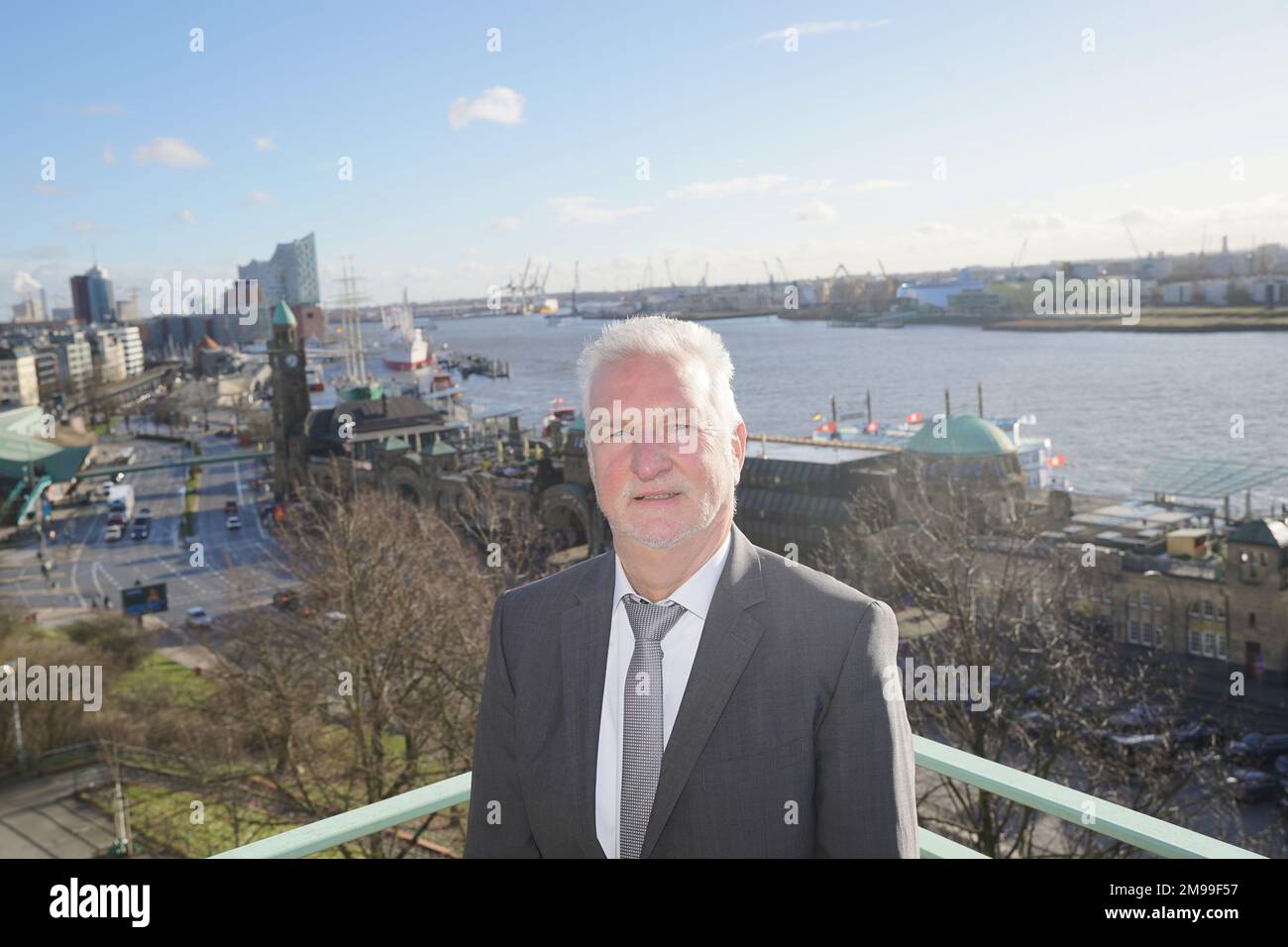 17. Januar 2023, Hamburg: Bernd Brügge, Leiter der Abteilung Ozeanografie und Vizepräsident des BSH, steht nach der jährlichen Pressekonferenz des BSH auf einem Balkon. Im Hintergrund sind der Landungsbrücken, die Überseebrücke und die Elbphilharmonie zu sehen. Die BSH sieht keine Möglichkeit, das Genehmigungsverfahren für das Dumping von Elbschlamm in der ausschließlichen Wirtschaftszone zu beschleunigen. Hamburg steht bei der Schlammbeseitigung unter einem gewissen Druck, weil die Vereinbarung über die Schlammentleerung am Seemarker E3 in der Nähe von Helgoland zeitlich und zeitlich begrenzt ist Stockfoto