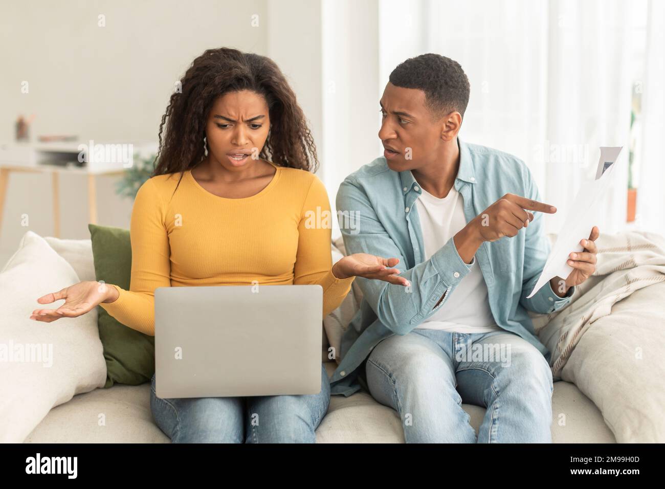 Traurig schockierte junge afroamerikanische Paar mit Laptop, Papiere frustriert wegen Fehlern in Buchhaltung und Steuern Stockfoto