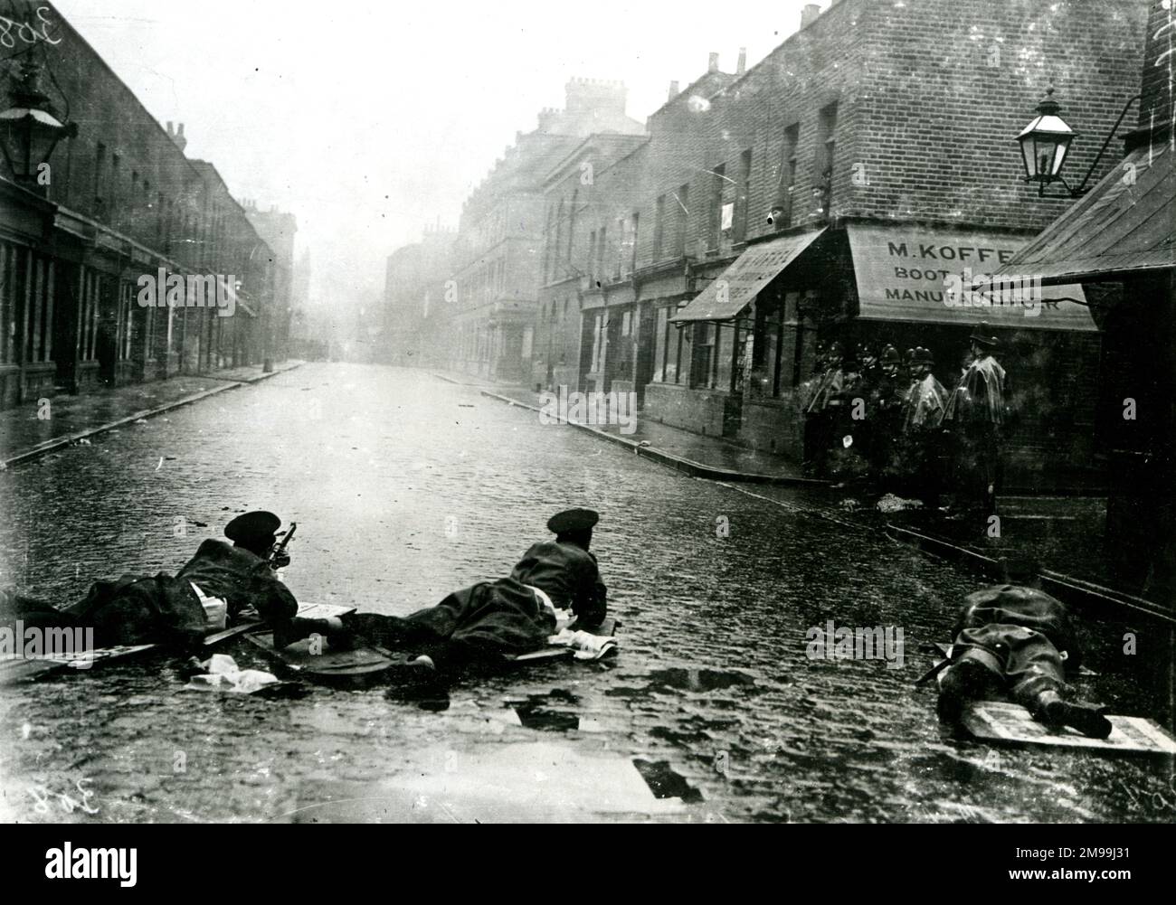 Während der Sidney Street Belagerung in London liegen Soldaten auf der kopfsteingepflasterten Straße, bereit zu schießen. Stockfoto