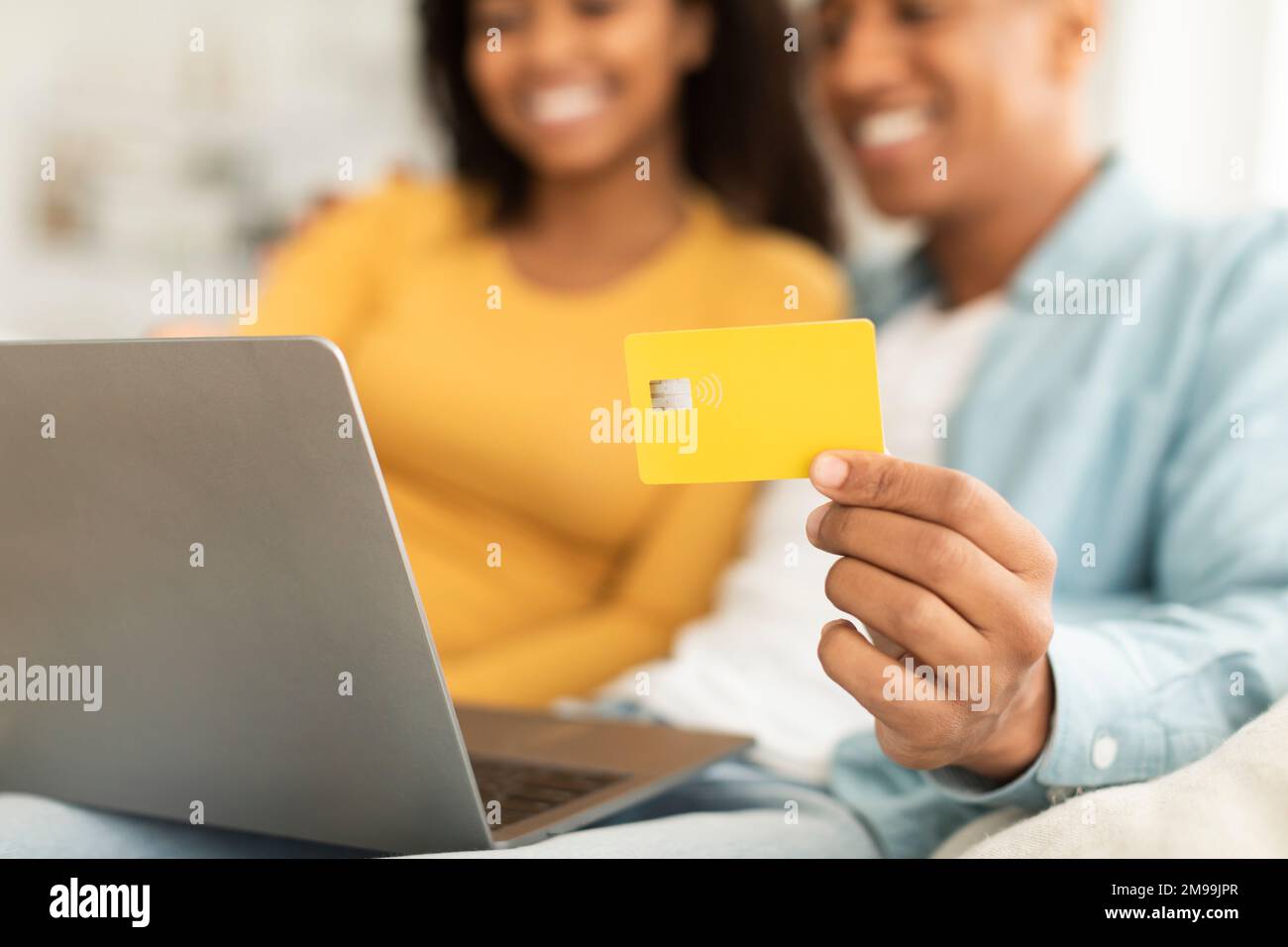 Glückliches junges afroamerikanisches Paar benutzte Kreditkarte und Laptop und überprüfte das Bankkonto im Zimmer Stockfoto