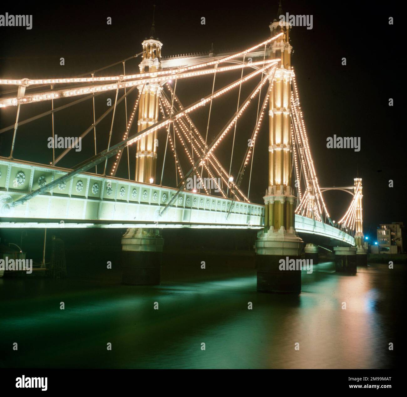 London - die Albert Bridge - beleuchtet bei Nacht. Blick von Chlesea am Nordufer der Themse in Richtung Battersea. Entworfen und erbaut von Rowland Mason Ordish im Jahr 1873 als Ordish-Lefeuvre-Brücke mit Kabelhalterungen Stockfoto