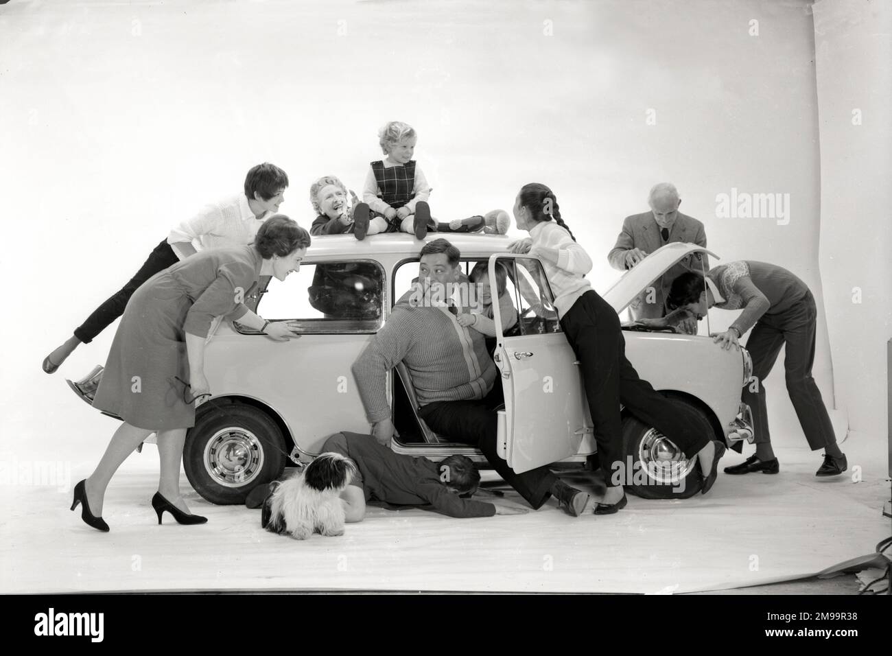 Werbung für CPV (Colman Prentis & Varley) – eine Gruppe von Personen (eine große Familie in verschiedenen Altersgruppen), die versuchen, sich in einen Austin (Mini) zu drängen (1/4). Stockfoto