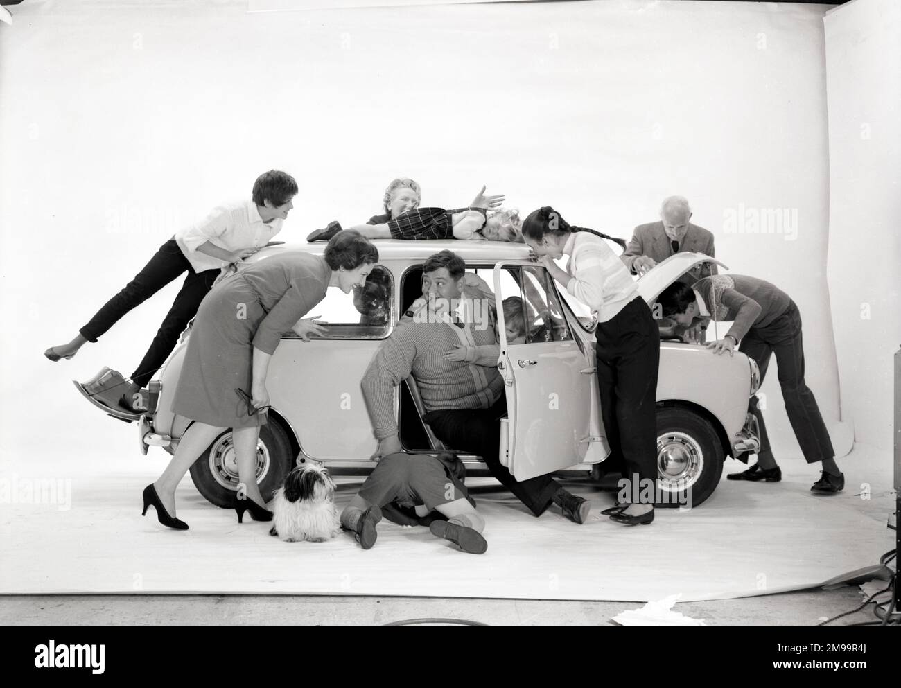Werbung für CPV (Colman Prentis & Varley) – eine Gruppe von Personen (eine große Familie in verschiedenen Altersgruppen), die versuchen, sich in einen Austin (Mini) zu drängen (3/4). Stockfoto