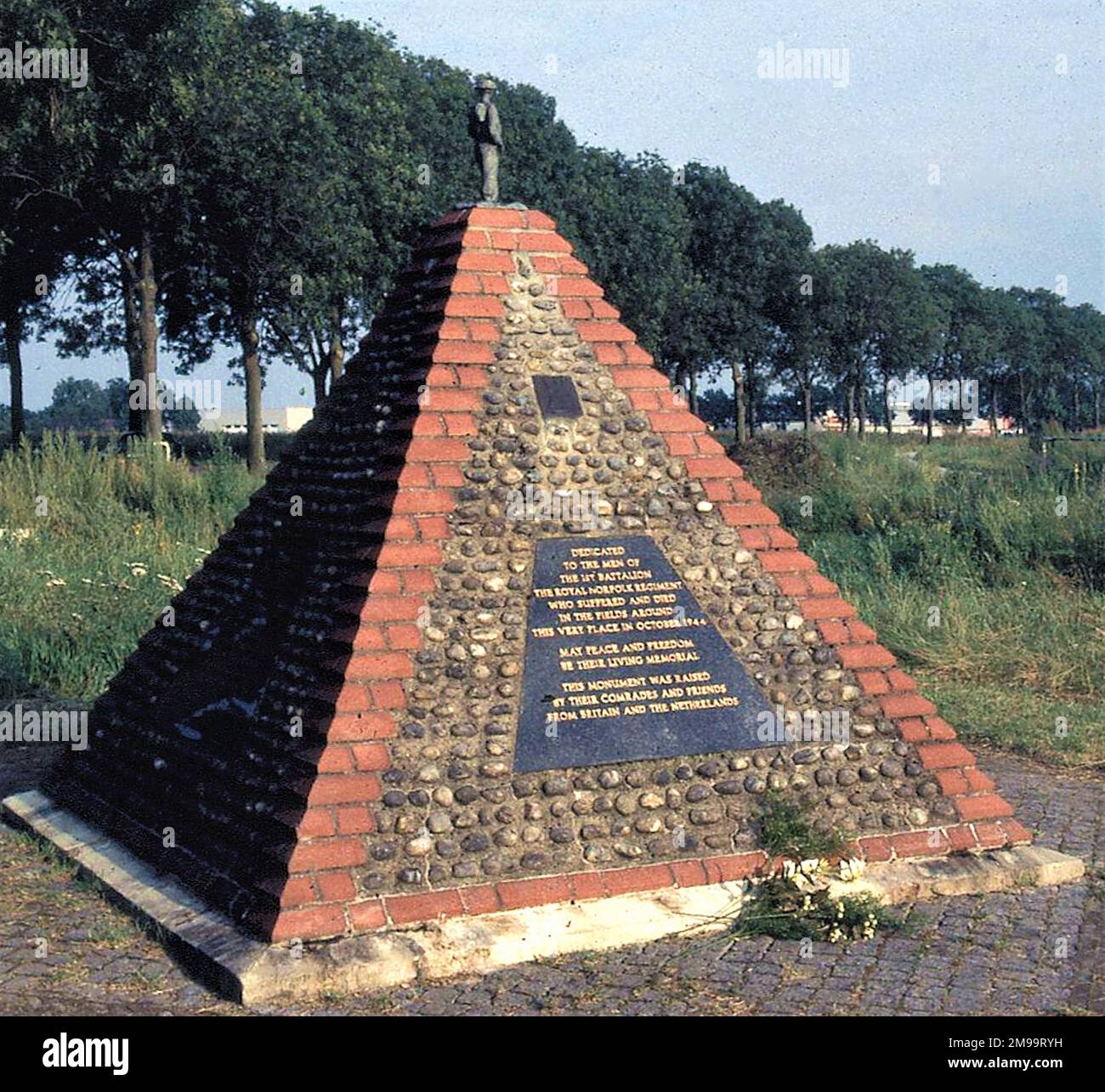 Die Ziegelpyramide wird von einer kleinen Figur eines britischen Soldaten gekrönt. Die Plaketten rund um die Pyramide sind den Männern des 1. Bataillons, dem Königlichen Norfolk-Regiment, gewidmet, die im Oktober 1944 auf den Feldern um diesen Ort litten und starben. Mögen Frieden und Freiheit ihr lebendiges Denkmal sein. Dieses Denkmal wurde von ihren Kameraden und Freunden aus Britiain und den Niederlanden errichtet." Es ist auch allen britischen, alliierten und niederländischen Soldaten gewidmet, die starben, um dieses Land frei zu machen, allen unschuldigen Kriegsopfern, insbesondere den 300 Zivilpersonen, die in und um Overloon und V getötet wurden Stockfoto