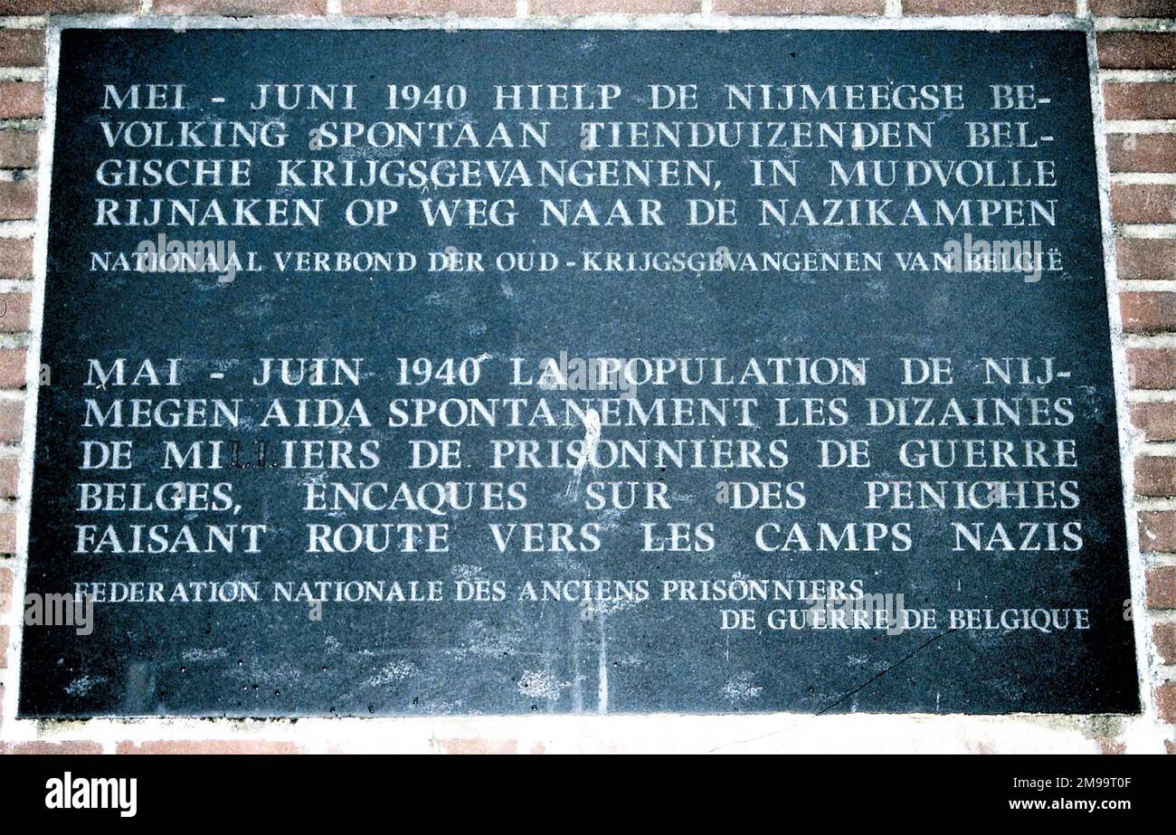 Die Inschrift auf der Tafel lautet: "Im Mai-Juni 1940 boten die Bürger von Nijmegen Zehntausenden belgischen Kriegsgefangenen spontan Hilfe auf ihrem Weg in Nazi-Lager in beengten Rheinschiffen an". Es wurde am 16. Mai 1992 vom belgischen Verband ehemaliger Kriegsgefangener errichtet." Zwischen dem 30. Mai und dem 5. Juni waren neunzig Schiffe mit einer Viertelmillion belgischer Kriegsgefangener am Waal-Kai festgemacht. Die Straßenbrücke wurde am 10. Mai von den Niederländern gesprengt und lag im Wasser und blockierte den Weg zu den Lagern in Deutschland. Bürger aus den umliegenden Bezirken von N Stockfoto