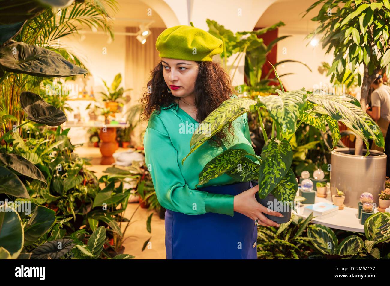 Junge Frau, die heimische grüne Pflanzen in einem Laden auswählt Stockfoto