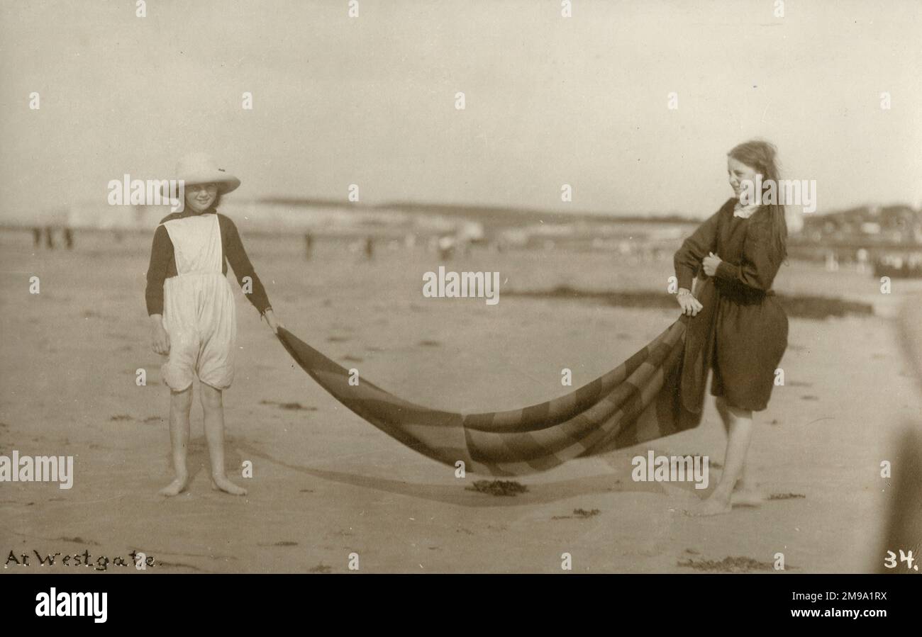 Two Girls legt eine gestreifte Decke am Strand von Westgate-on-Sea im Nordosten von Kent, England. Stockfoto