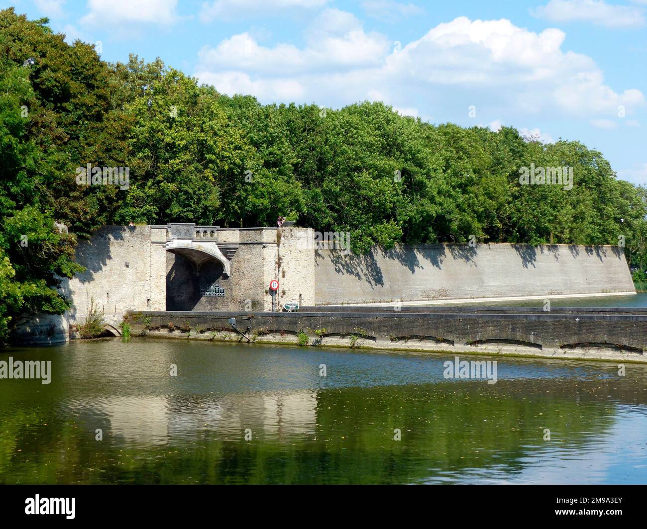 Ypern ist eine von Mauern umgebene Stadt mit mehreren Routen. Die beiden bekanntesten Tore durch die Stadtmauern sind das Menin-Tor (an der alten Straße nach Menin) und das Lille-Tor (an der alten Straße nach Lille). Entgegen der öffentlichen Meinung taten die meisten britischen Truppen, die sich auf den Salient zubewegten, dies über dieses Tor, da das Menin-Tor dem Granatfeuer des Feindes besonders ausgesetzt war. Die Säulen auf beiden Seiten des Bogens stammen aus dem Jahr 1395 und die Stadtmauern wurden von Vauban umgestaltet. Stockfoto