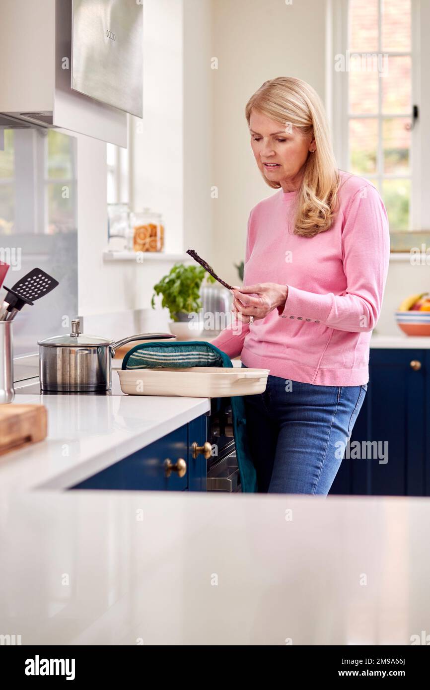 Menopausale Reife Frau Mit Schlechter Gedächtnisverbrennung Im Ofen Zu Hause Stockfoto