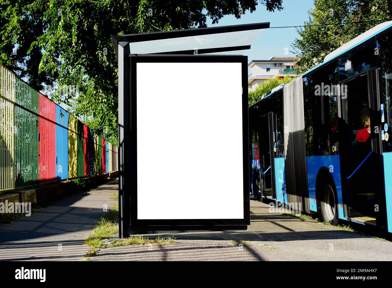 Busunterkunft mit Lightbox-Anzeigeschild. Modellhintergrund. Werbetafel aus Glas mit leerer weißer Anzeigefläche. Blauer Bus an der Bushaltestelle. Schild für den Außenbereich Stockfoto