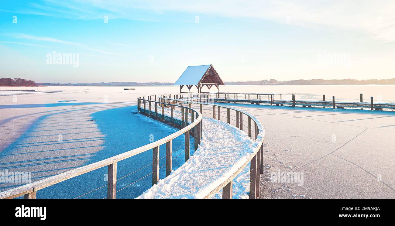 Gefrorener See im Winter mit Fußgängerbrücke an sonnigen Tagen. Hochwertiges Foto Stockfoto