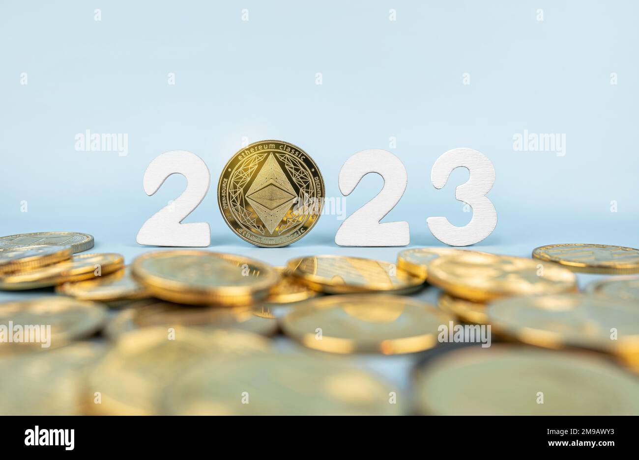 Ethereum-2023-Preisvorhersagekonzept. Äthermünze neben Kryptowährungs-Token und Jahreszahlen auf blauem Hintergrund. Nahaufnahme, Soft Focus. Stockfoto