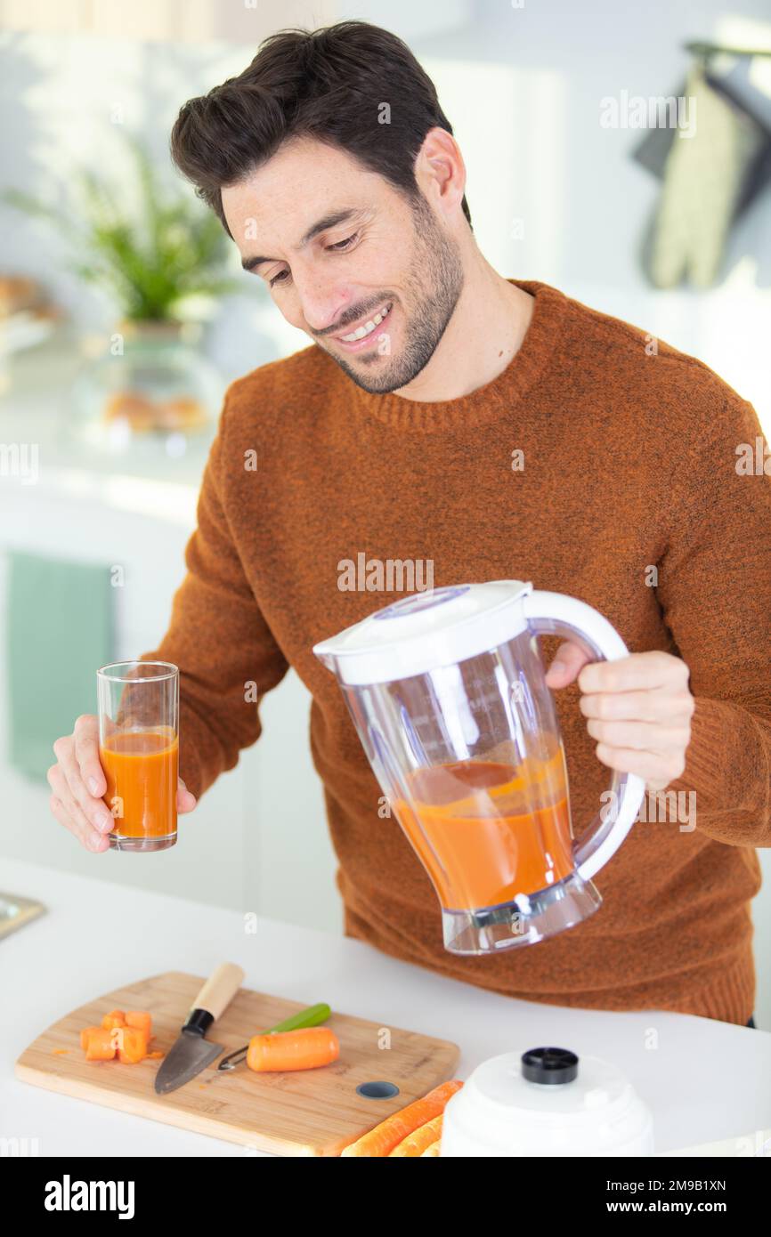 Junger bärtiger Mann trinkt frisch gepressten Natursaft Stockfoto