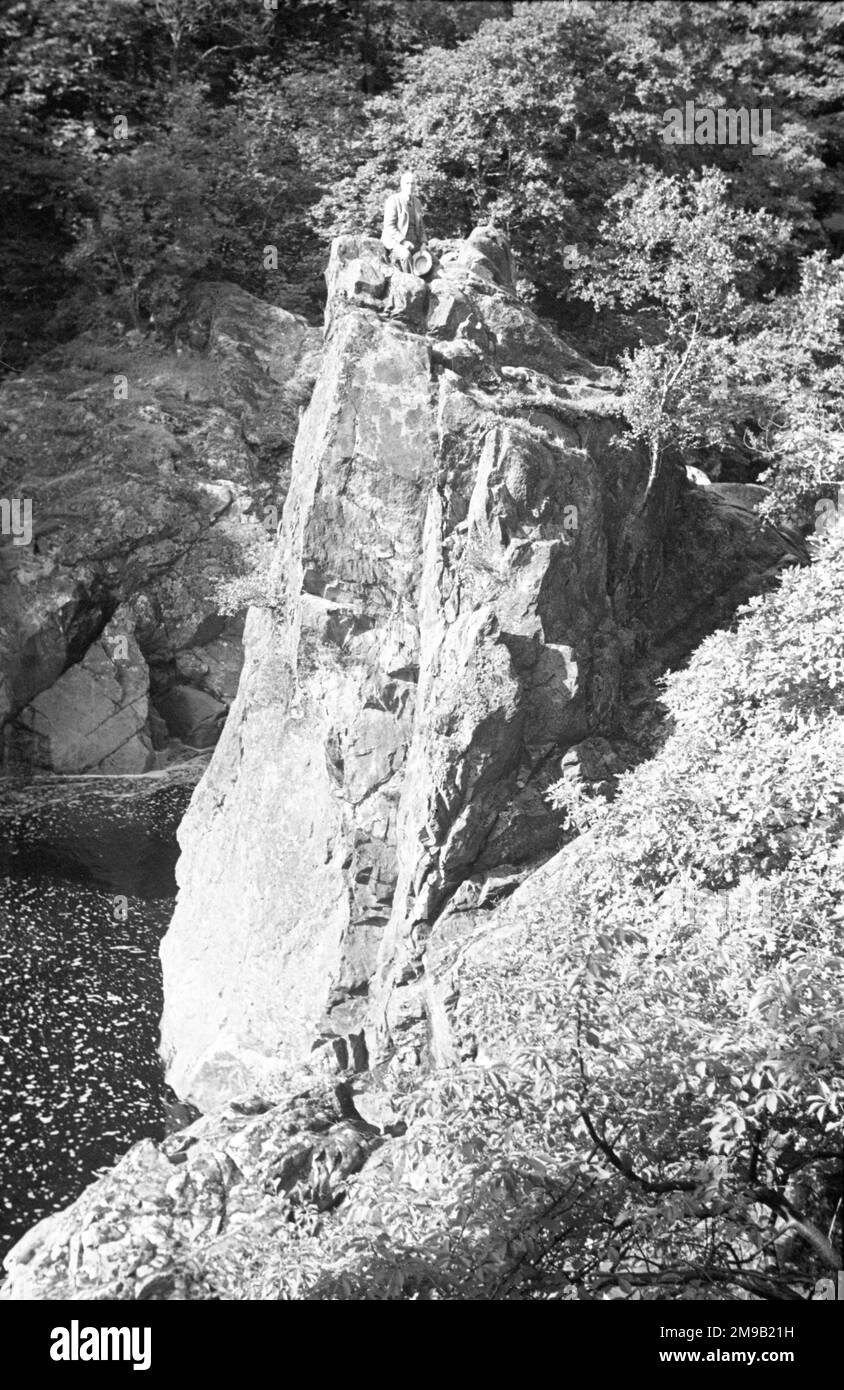 Schottische Hügel und Seen: - Schottischer Gentleman, der auf einem Felsen ruht, über einem Gebirgskuchen Stockfoto