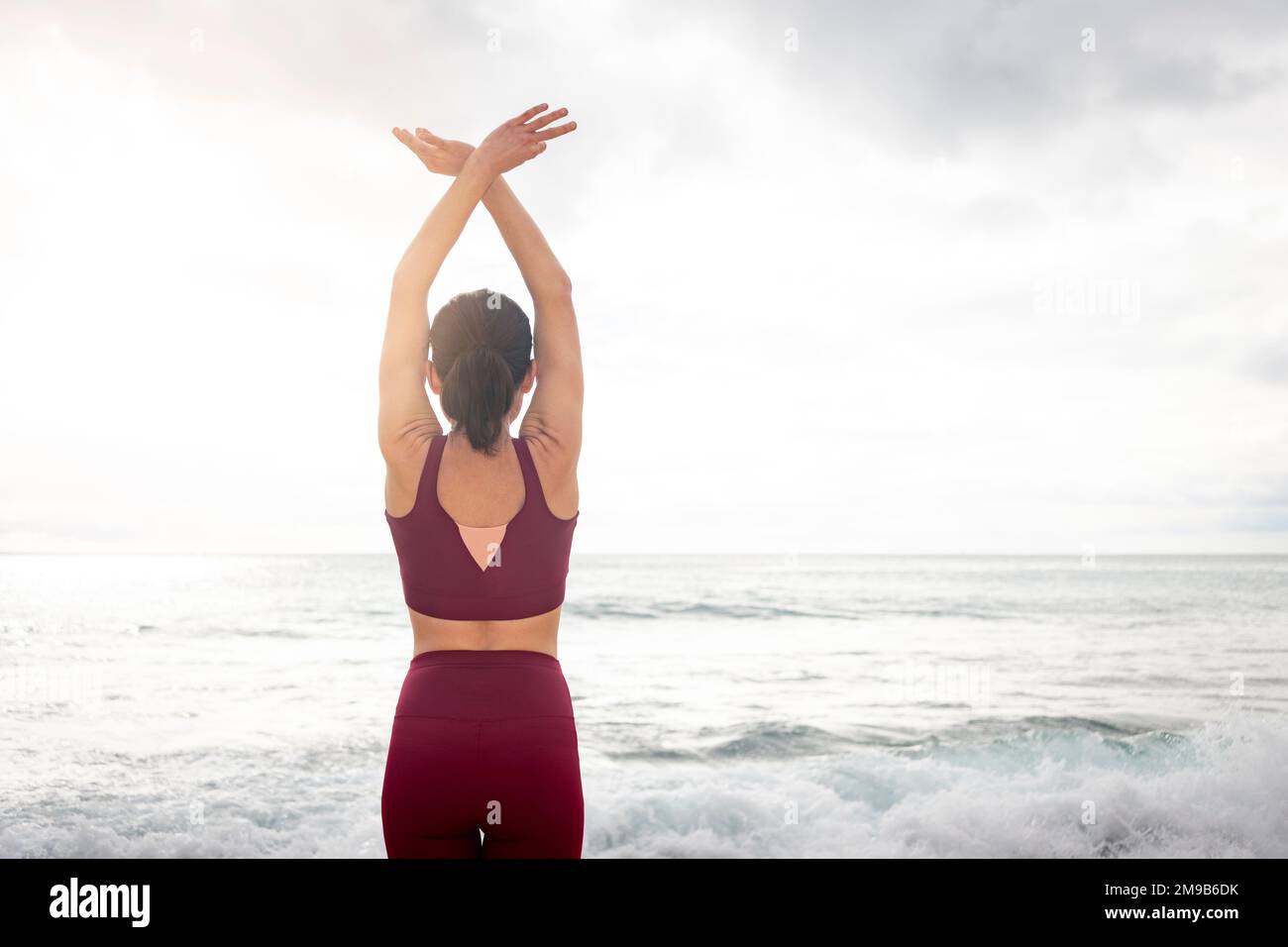 Eine Frau, die Yoga-Meditation macht, mit Blick auf das Meer, Rückansicht. Stockfoto