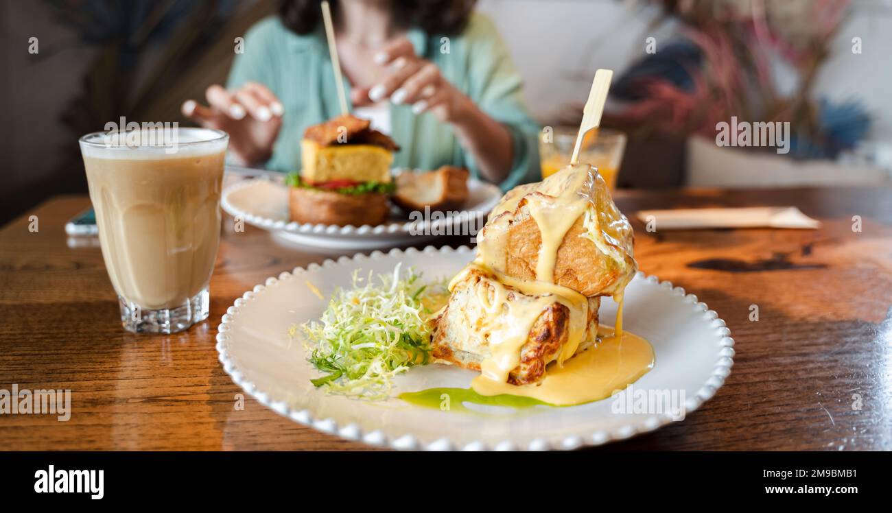 Trendiges Frühstück im hippen Restaurant, Café. Kreatives quadratisches Croissant in Form eines Würfels auf Spieß. Serviert mit heißem Käse in einem kleinen Saucen-Boot, Stockfoto