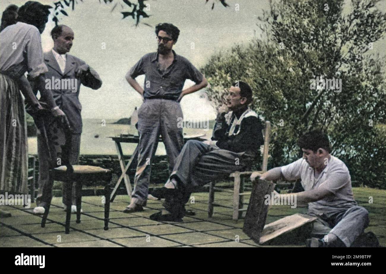 Salvador Dali (1904 - 1989), der surrealistische Künstler, wird abends nach einem Arbeitstag in seinem Sommerhaus in Port Lligat am Fuße der spanischen Pyrenäen gezeigt. Auf der linken Seite steht der katalanische Schriftsteller J. V. Foix. Auf der rechten Seite bereitet sich einer der jungen Schüler des Meisters darauf vor, seine Arbeit zu zeigen. Stockfoto