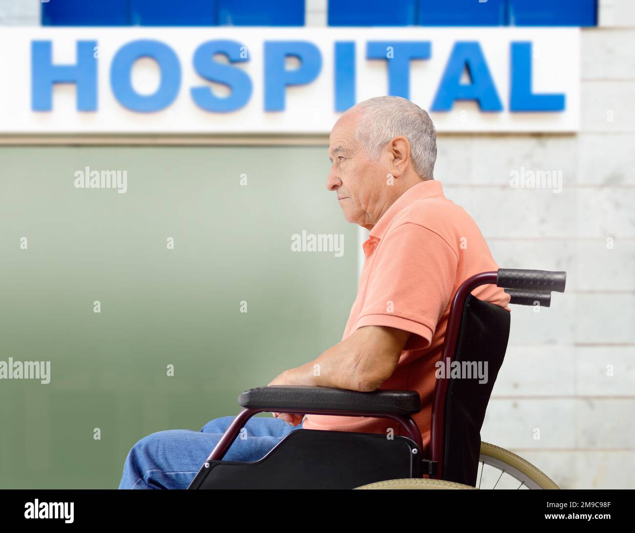 Der ältere Patient auf einem Rollstuhl wartet neben dem Krankenhausgebäude Stockfoto