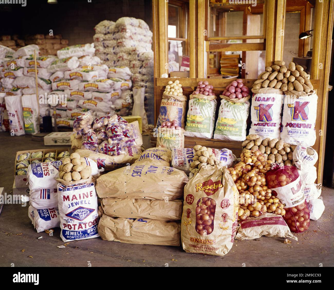 1960S TÜTEN ZWIEBELN UND KARTOFFELN IN EINEM LEBENSMITTELVERTEILUNGSZENTRUM - KF6170 HAR001 HARS ZWIEBELN Stockfoto