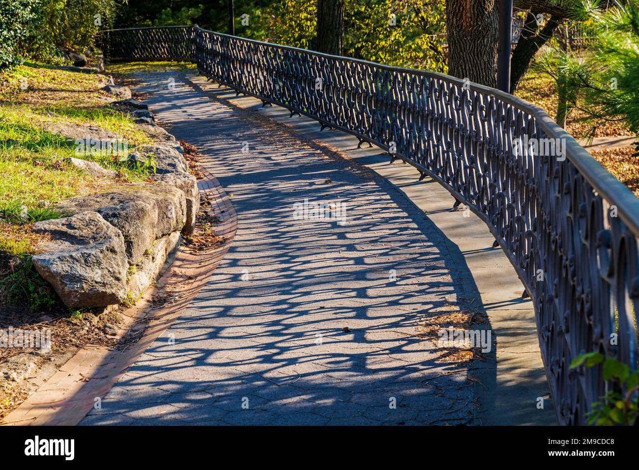 Die Sonne wirft lange Schatten auf den leeren eingezäunten Weg entlang der Fairmount Water Works in Philadelphia, Pennsylvania, USA Stockfoto