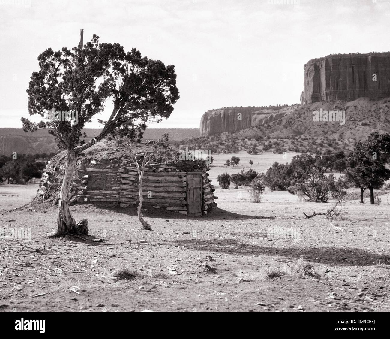 1930S TRADITIONELLES NAVAJO HOGAN AUF STAMMESRESERVAT IN DER NÄHE VON GALLUP NEW MEXICO USA - L1279 HAR001 HARS BUILDINGS SPIRITUALITY B&W NORTH AMERIKA NORDAMERIKANISCHE TRÄUME MEXIKO STRUKTUR WELLNESS-ABENTEUER RELIGIÖSE EXTERIEUR WISSEN REICHTUM HOLZHÄUSER IN DER NÄHE DER PRIMÄREN GLÜCKSKULTUR GALLUP RESERVAT RESIDENZ MIT AUFSTEIGENDER SONNENAUFGANGSSONNE, KEGELFÖRMIGE WOHNUNGEN, STAMMESWÄNDE, DIE IN SCHWARZ UND WEISS ZEREMONIELL VON HAR001 HOGAN ALTMODISCH GEHALTEN WERDEN Stockfoto