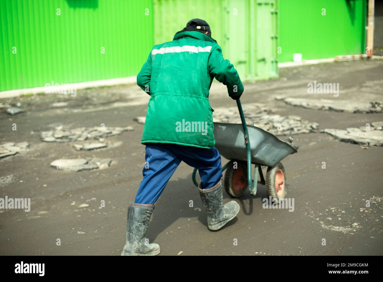 Baumeister entfernt gebrochenen Stein. Der Mann trägt Kopfsteinpflaster im Wagen. Stockfoto