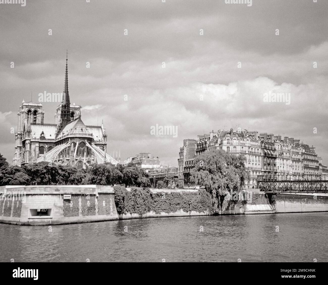 1970S-GRAD-BLICK VON DER KATHEDRALE NOTRE DAME AUF DER ILE DE LA CITÉ UND DEN GEBÄUDEN AUF DER ILE SAINT-LOUIS PARIS FRANKREICH SEINE-FLUSS - R22018 HAR001 HARS IMMOBILIEN DE BAUTEN SEINE-GEBÄUDE TREU SYMBOLISCH ZITIEREN GLAUBE FLIEGENDE STÜTZPFEILER FRANZÖSISCH GOTISCHER GLAUBE SCHWARZWEISS KATHOLISCH AUS DEM JAHR HAR001 BEKANNTE, ALTMODISCHE UNESCO-WELTKULTURERBESTÄTTE LA NOTRE DAME Stockfoto