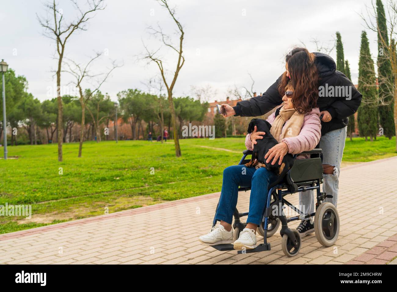 Ein Mädchen, das Fotos mit ihrer Großmutter im Rollstuhl macht Stockfoto