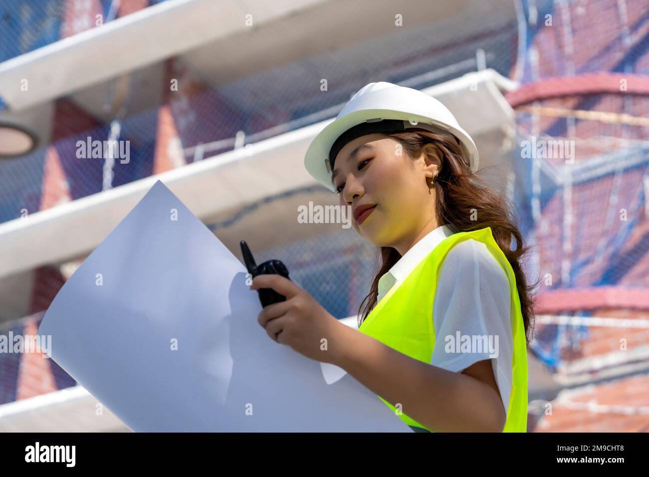 Weibliche Architektin, die sich Baupläne ansieht Stockfoto