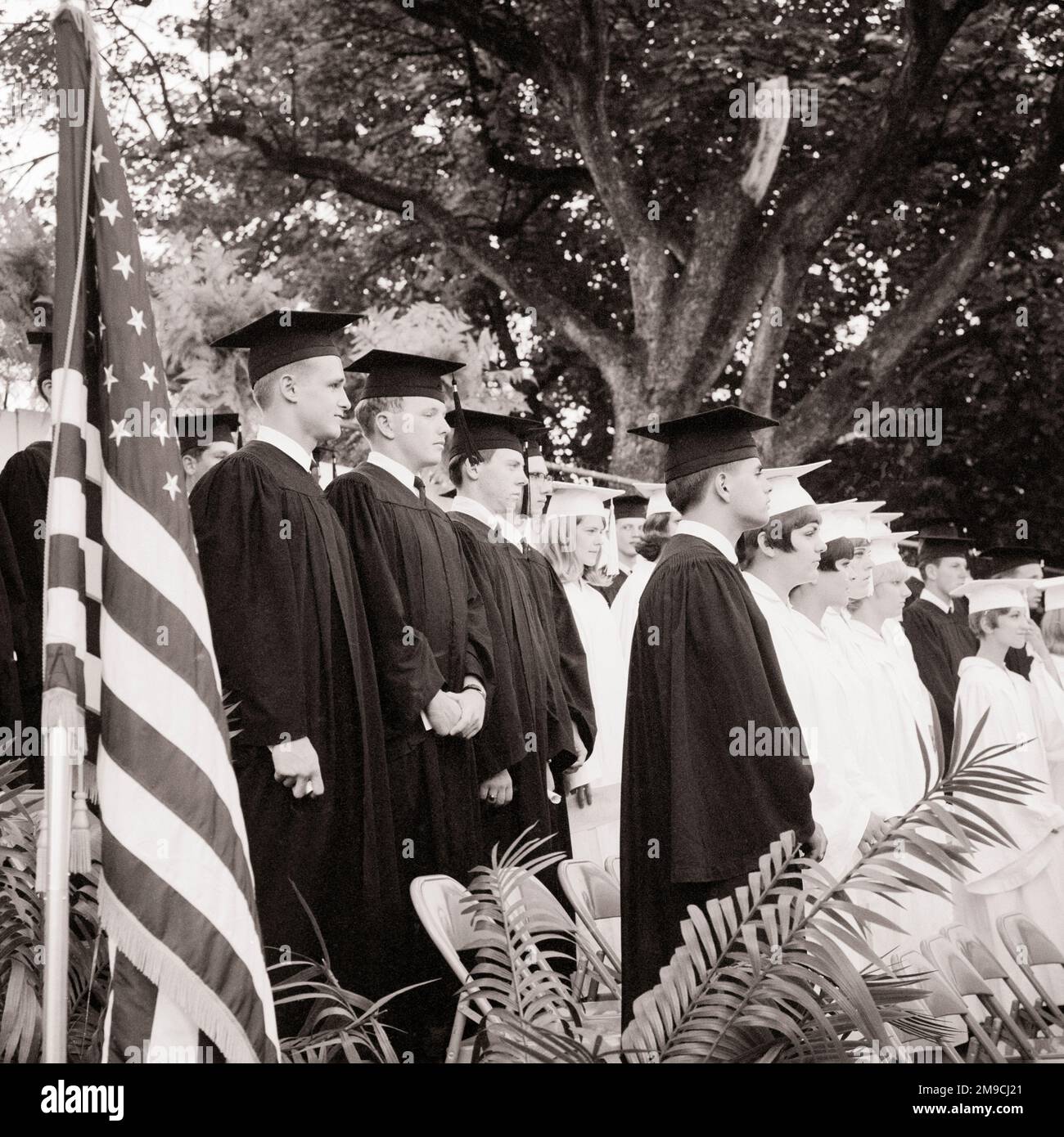 1960S HIGH SCHOOL-JUNGEN IN SCHWARZEN BADEMÄNTELN MÄDCHEN IN WEISSER OUTDOOR-FLAGGE - S17580 HAR001 HARS-FRAUEN-DIPLOM UNITED STATES COPY SPACE FRIENDSHIP PERSONEN MIT HALBER LÄNGE INSPIRATION UNITED STATES OF AMERICA MÄNNER TEENAGER TEENAGE BOY, DER B&W NORTH STUDIERT AMERIKA FREIHEITSZIELE NORDAMERIKANISCHE SCHULEN ERFOLG TRÄUME GLÜCK UMHÜLLT AUFREGUNG WISSEN FÜHRUNGSSTOLZ GELEGENHEIT HIGH SCHOOL HIGH SCHOOL KONZEPT STERNE UND STREIFEN TEENAGER MORTARBOARD OLD GLORY KOOPERATION WACHSTUM ROT WEISS UND BLAU ZUSAMMENGEHÖRIGKEIT SCHWARZ UND WEISS KAPPE UND KLEID KAUKASISCHE ETHNISCHE ZUGEHÖRIGKEIT HAR001 Stockfoto